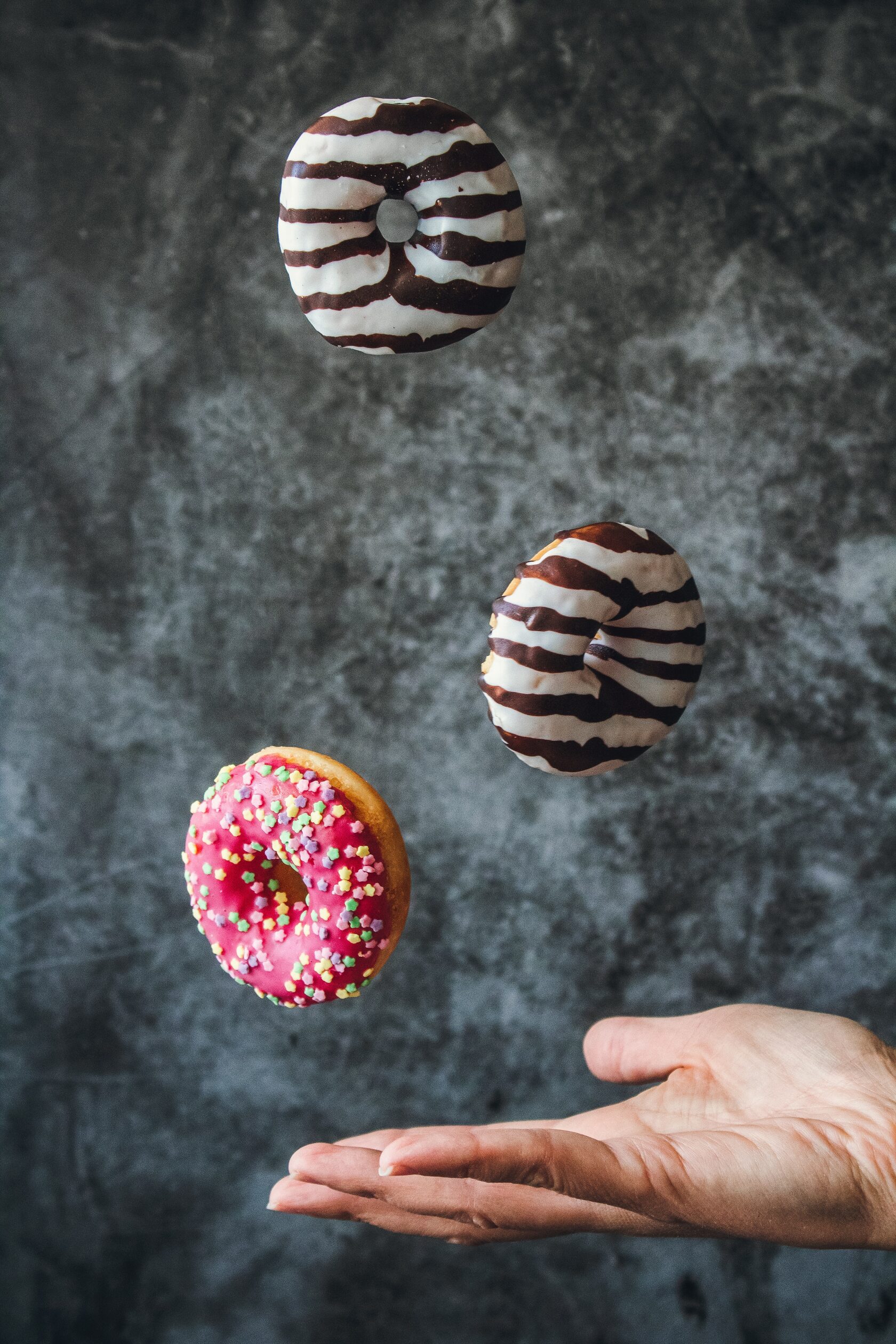Glazed doughnuts suspended above an outstretched hand Glazed doughnuts suspended above an outstretched hand