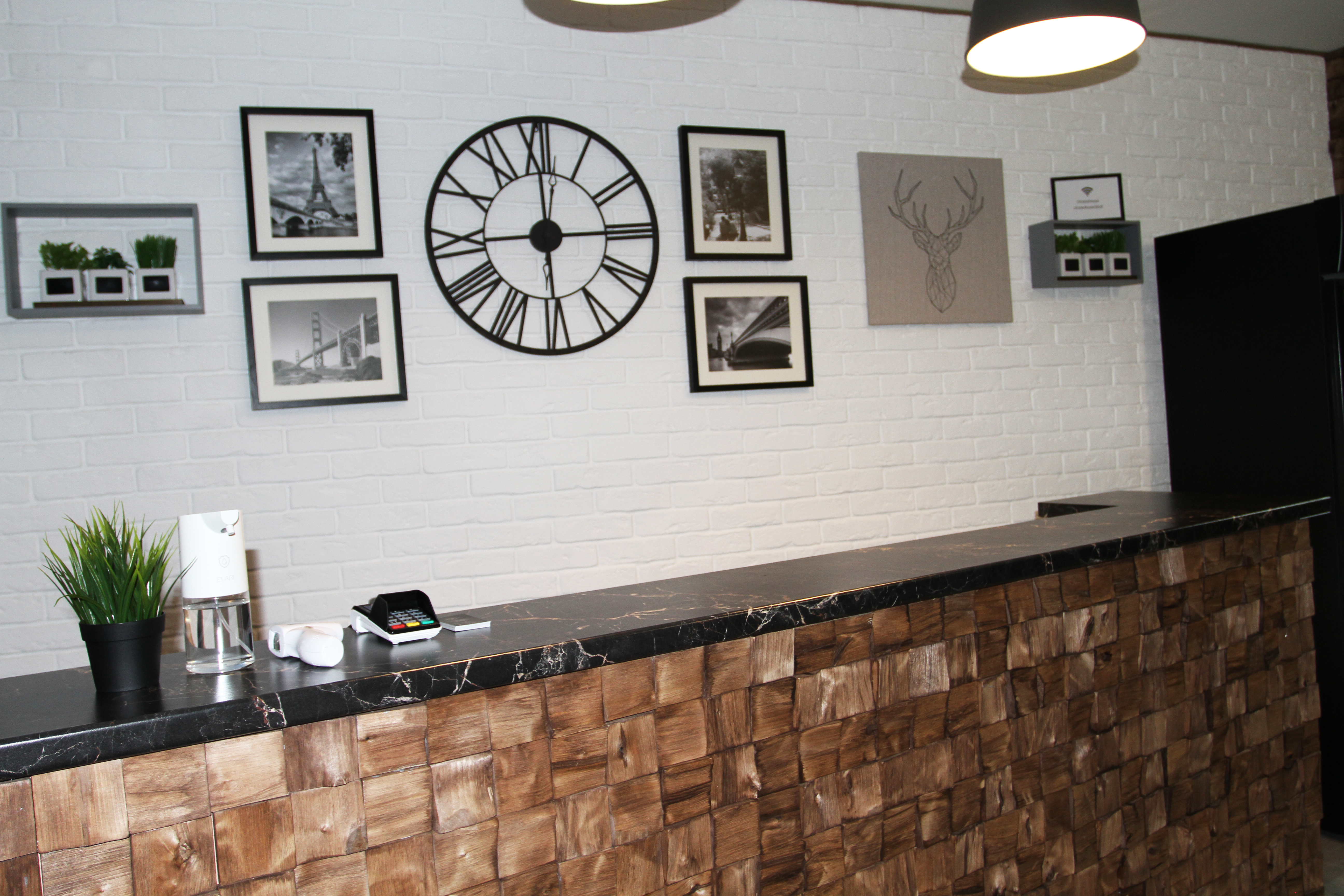 Hostel reception desk with a wall clock and framed photographs