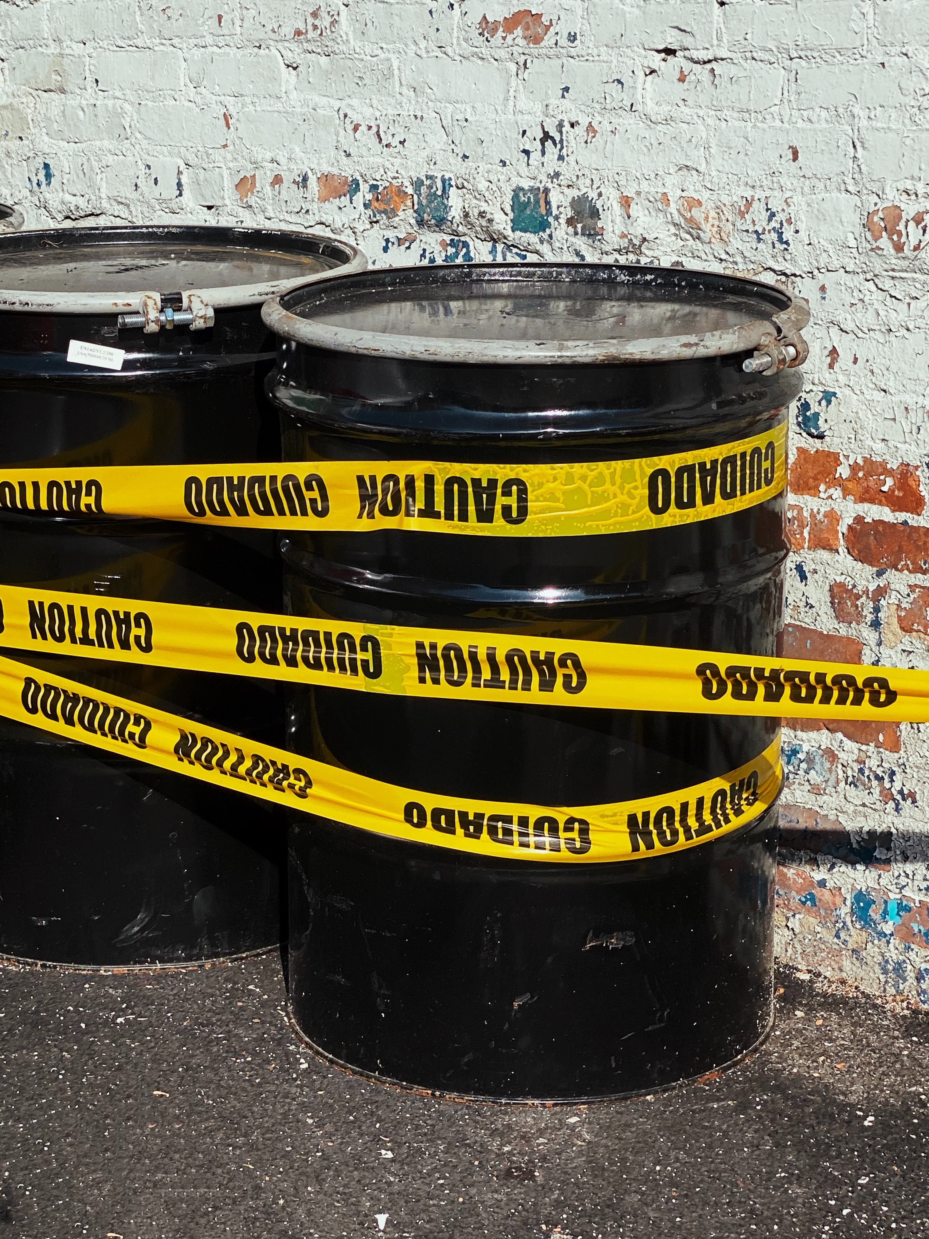 Black industrial barrels wrapped in yellow caution tape Black industrial barrels wrapped in yellow caution tape