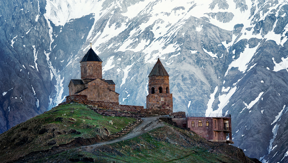 A hilltop church against snow-covered mountains in Georgia